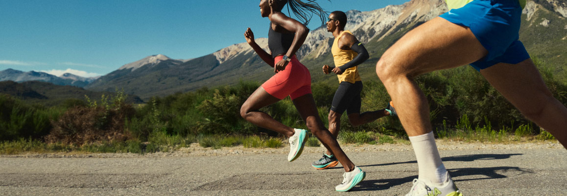 Three runners on a road, with mountains in the distance.