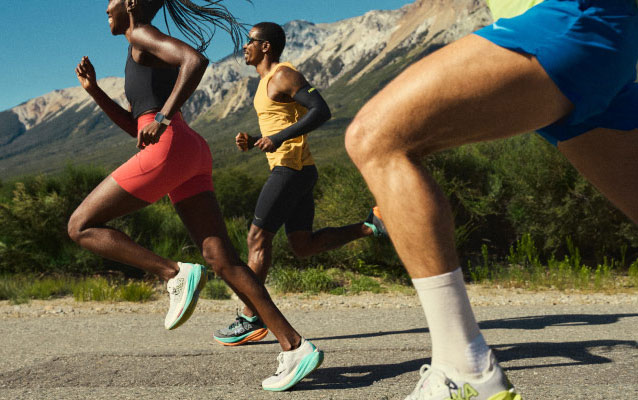 Three runners on a road, with mountains in the distance.